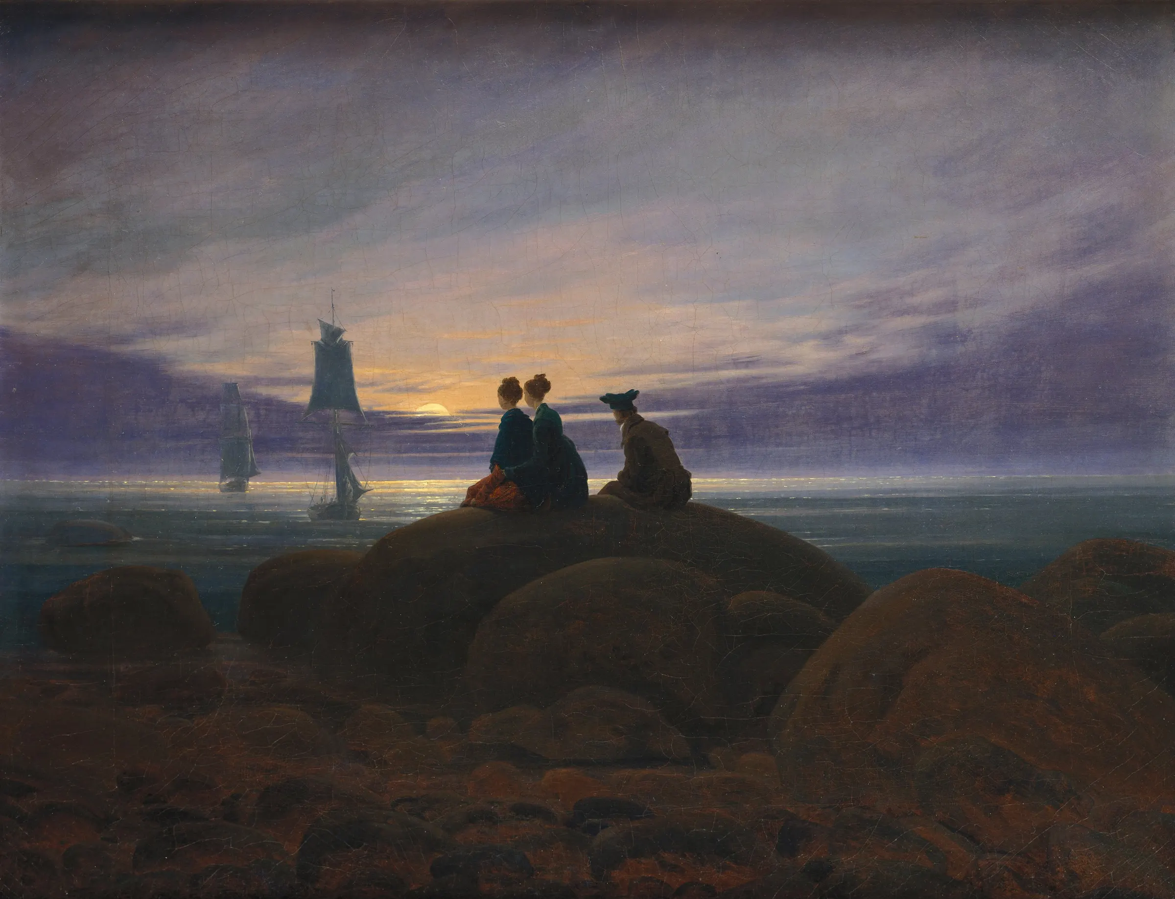 Three figures on a rocky shore at dusk watch two ships return under a violet-blue sky tinged with the warm glow of the rising moon.