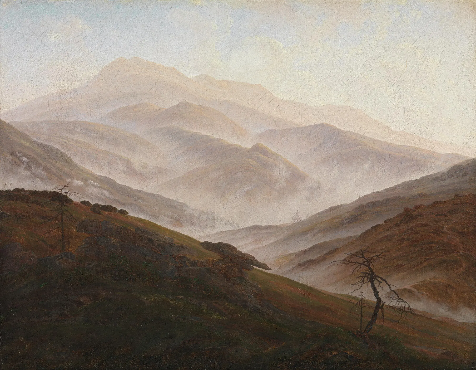 A succession of mountain ridges fading into pale fog, the valleys still hidden, daylight just arriving.
